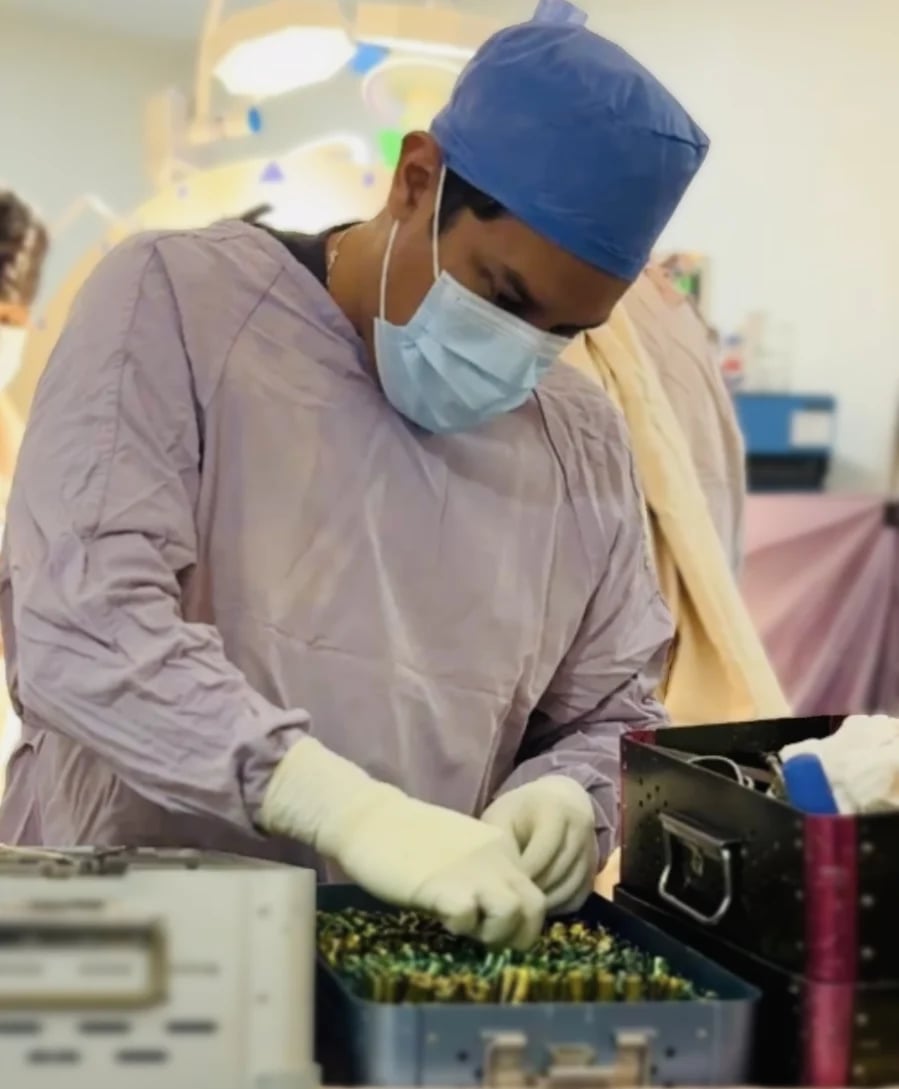 Healthcare worker in surgical attire examining plant samples in laboratory setting